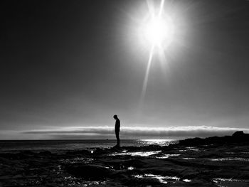 Silhouette man standing by sea against sky