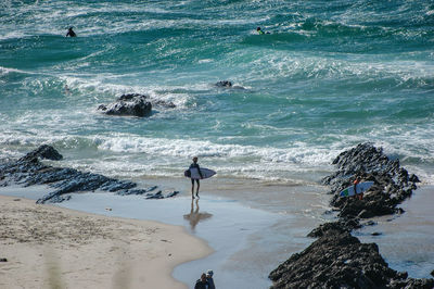 Surfer walking at sea shore