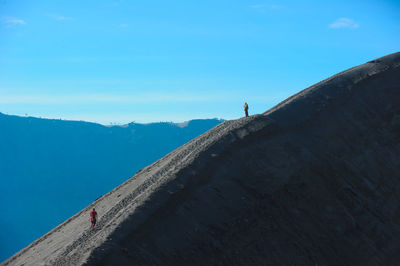 Rear view of people standing on landscape against clear blue sky