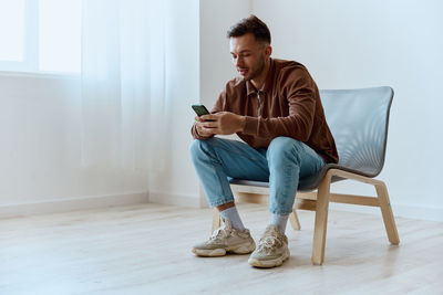 Young man using mobile phone while sitting on floor