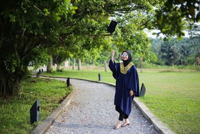 Full length of young woman photographing through mobile phone