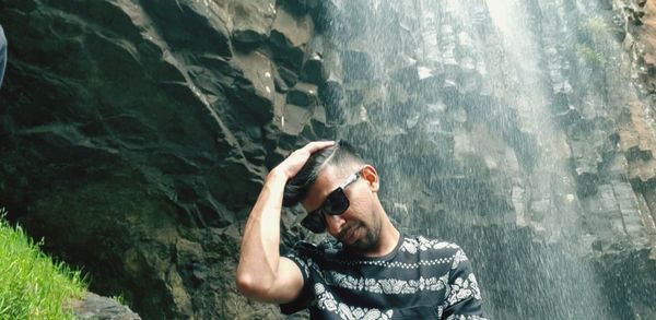 Portrait of young man looking at waterfall