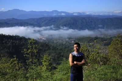 Portrait of young man standing against mountains