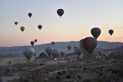 Hot air balloons flying over landscape against sky during sunset