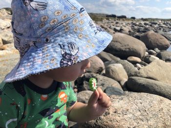 Close-up of baby boy eating lollipop while sitting on rock