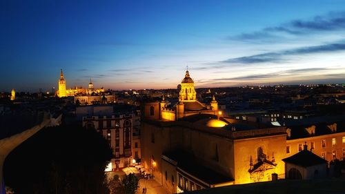 View of illuminated cityscape against sky during sunset