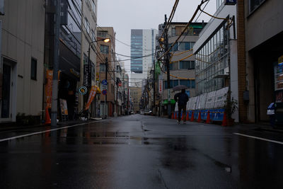 Wet street amidst buildings in city during rainy season