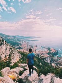 Rear view of man standing on mountain against sky