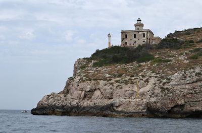 Lighthouse by sea against sky