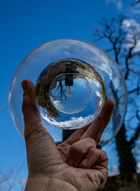 Close-up of hand holding glass against blue sky