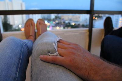 Low section of people sitting against sky