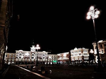 Illuminated street amidst buildings in city at night