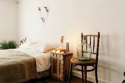 Minimalist style home bedroom interior design with cozy bed and wooden furniture placed near white wall with boho decorations