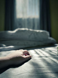 Cropped hand of person on bed at home