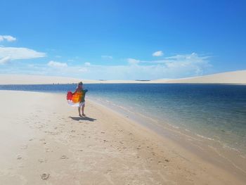 Rear view of woman on beach against sky