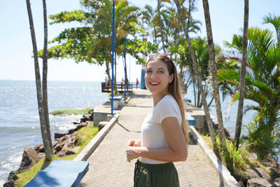 Portrait of smiling young woman standing against sea