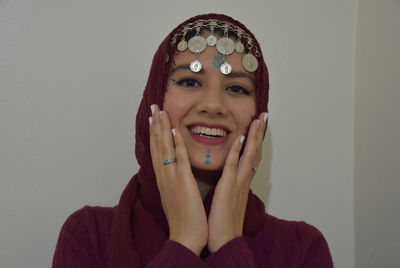 Portrait of a smiling young woman against wall