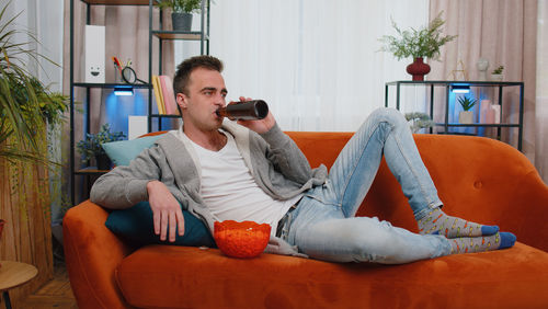 Young man drinking beer while watching movie