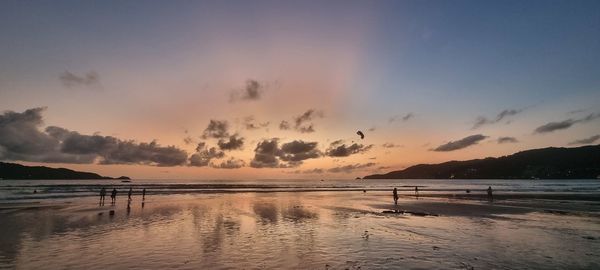 Sunse on patong beach, with parasailing in the golden sky with people on the beach 