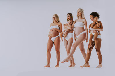 Low angle view of female friends standing against white background
