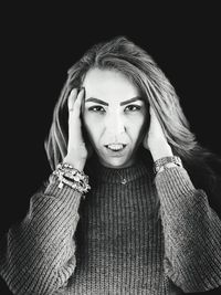 Portrait of woman standing against black background