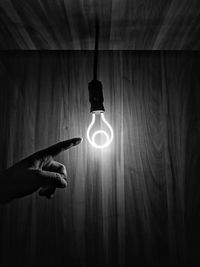 Person holding illuminated electric lamp against wall