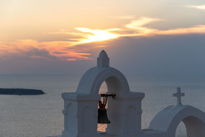 Cross by sea against sky during sunset