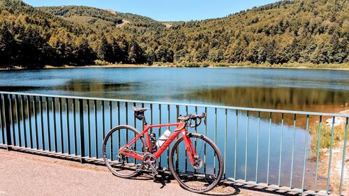 Bicycle parked by railing against lake