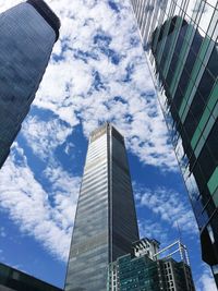 Low angle view of skyscrapers against cloudy sky