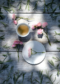 High angle view of coffee cup with flowers and leaves on wooden table