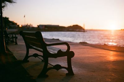 Empty chairs on beach against sky during sunset