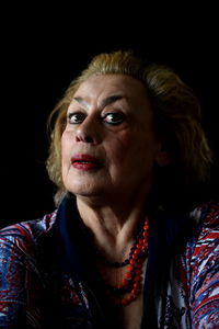 Close-up portrait of serious young woman over black background