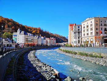 River amidst buildings against blue sky