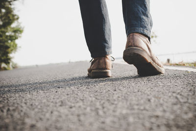 Low section of man wearing shoes on road