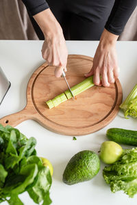 Healthy eating, dieting concept. high angle view of female hands cutting celery in the kitchen