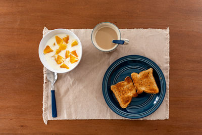 Healthy breakfast with orange, coffee and toasts, on wood.