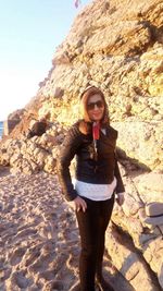 Woman standing on rock at beach against sky