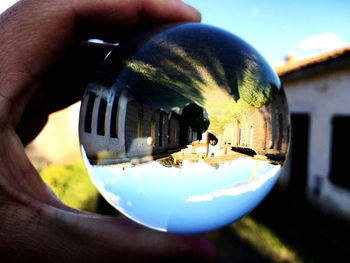 Reflection of person holding ball on glass