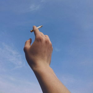 Low angle view of human hand holding blue sky