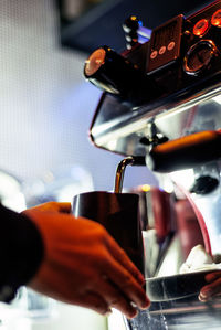 Cropped hand taking coffee from machinery