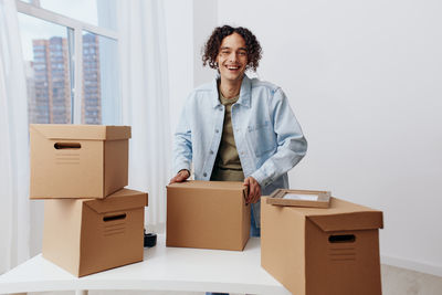 Portrait of smiling young woman holding box against white background