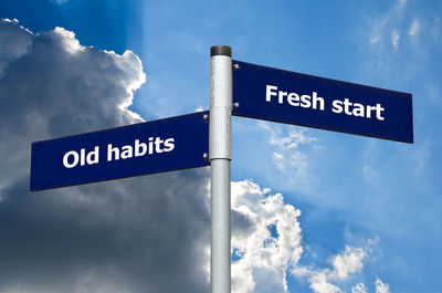 Low angle view of road sign against blue sky