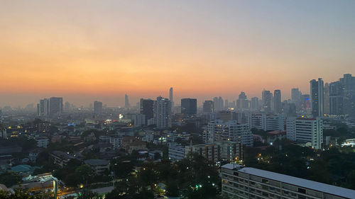 Modern buildings in city against sky during sunset