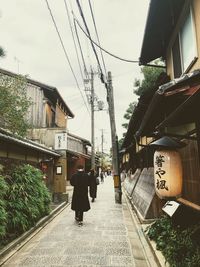 Rear view of people walking on street amidst buildings in city