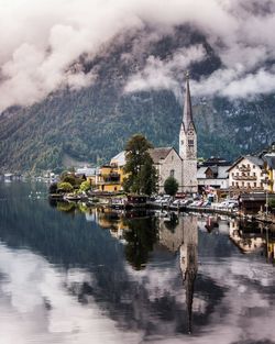Historic church by calm lake at hallstatt village