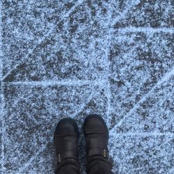 Low section of person standing snow covered footpath