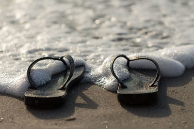 Close-up of flip-flops on sand at beach