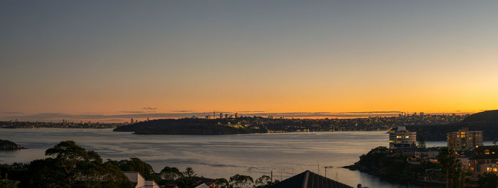 Scenic view of river by buildings against sky during sunset