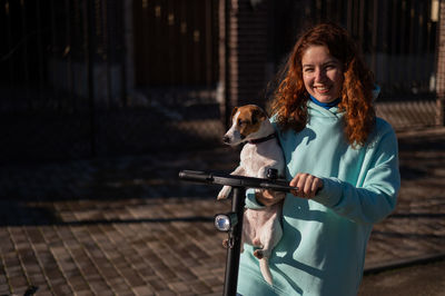 Portrait of young woman with dog on street