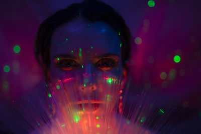 Portrait of beautiful young woman against illuminated background